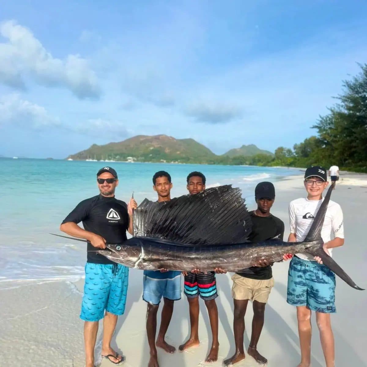 The crew holding a sailfish on the beach after a trolling trip