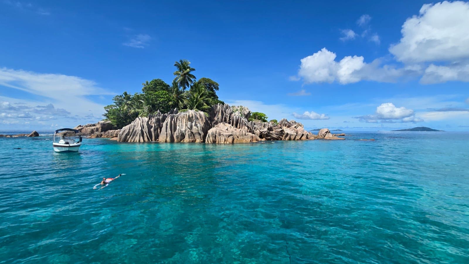 The granite islet of St. Pierre in turquoise water with a boat moored alongside